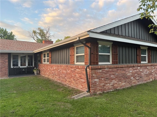 912 Circle Dr, Independence, KS 67301 - view of side of property with board and batten siding, brick siding, and a yard