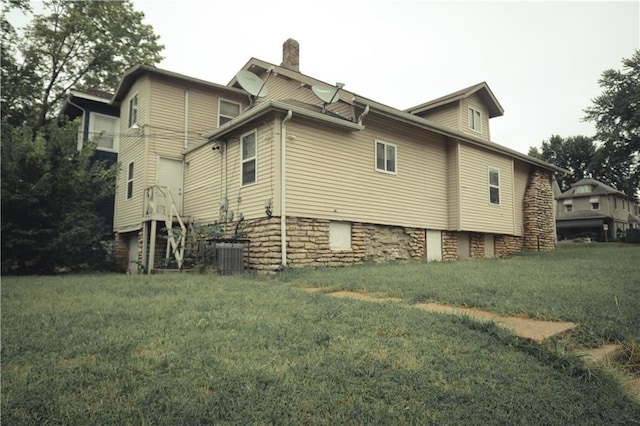3344 S Benton Ave, Kansas City, MO 64128 - view of home's exterior with a lawn, a chimney, and central AC unit