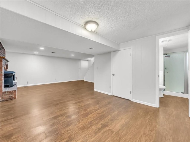 finished basement featuring baseboards, stairway, wood finished floors, and a textured ceiling
