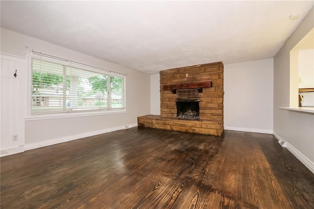 unfurnished living room with wood finished floors, baseboards, and a stone fireplace