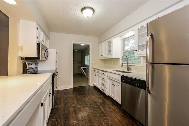 kitchen featuring glass insert cabinets, tasteful backsplash, appliances with stainless steel finishes, a sink, and dark wood-style floors