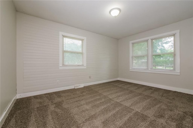 empty room with visible vents, baseboards, and dark colored carpet