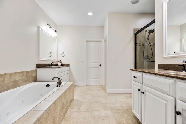 full bath featuring a jetted tub, a sink, two vanities, and a shower stall