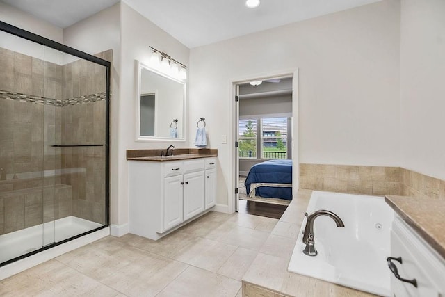 ensuite bathroom featuring tile patterned flooring, vanity, a jetted tub, baseboards, and a stall shower