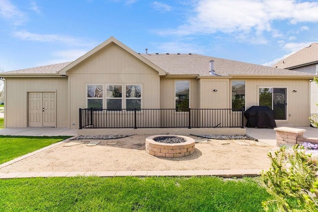 back of house with a patio, a shingled roof, and an outdoor fire pit