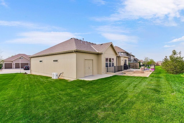 back of property featuring a patio, a lawn, and roof with shingles
