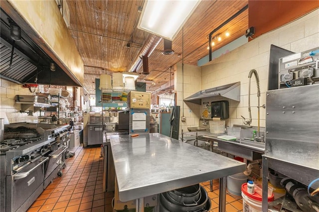 kitchen with ventilation hood, stainless steel counters, range with two ovens, and tile patterned floors