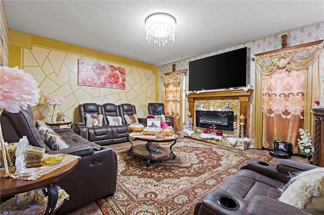 living room featuring a glass covered fireplace, wallpapered walls, and a textured ceiling