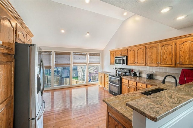 401 NW 51st St, Gladstone, MO 64118 - kitchen featuring appliances with stainless steel finishes, a sink, backsplash, stone countertops, and light wood finished floors