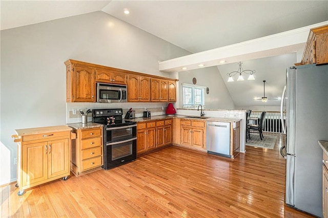 401 NW 51st St, Gladstone, MO 64118 - kitchen featuring appliances with stainless steel finishes, a sink, a peninsula, ceiling fan, and light wood-style flooring