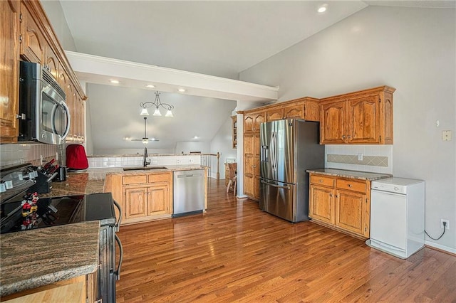 401 NW 51st St, Gladstone, MO 64118 - kitchen with appliances with stainless steel finishes, vaulted ceiling, a peninsula, a sink, and wood finished floors