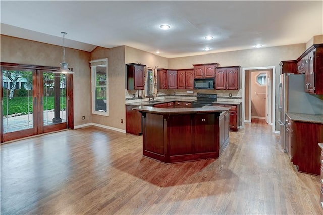 kitchen featuring baseboards, light wood finished floors, and black appliances