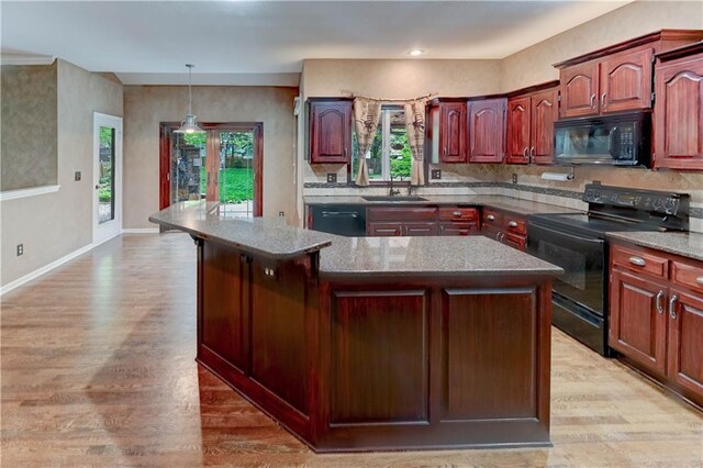kitchen with a wealth of natural light, a sink, black appliances, and light wood-style floors