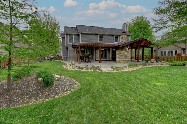 back of house with a patio, a lawn, fence, and a chimney