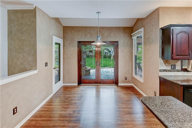 doorway featuring baseboards and wood finished floors