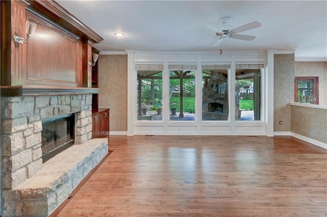 unfurnished living room with a healthy amount of sunlight, baseboards, a fireplace, and wood finished floors