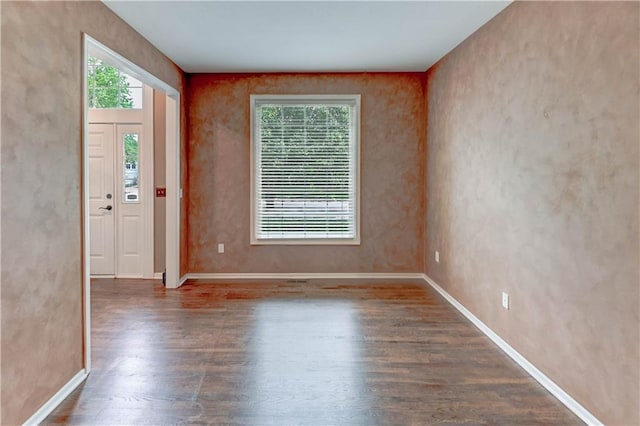spare room with baseboards, plenty of natural light, and wood finished floors