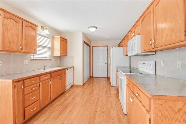 kitchen with white appliances, a sink, light wood-type flooring, tasteful backsplash, and light countertops