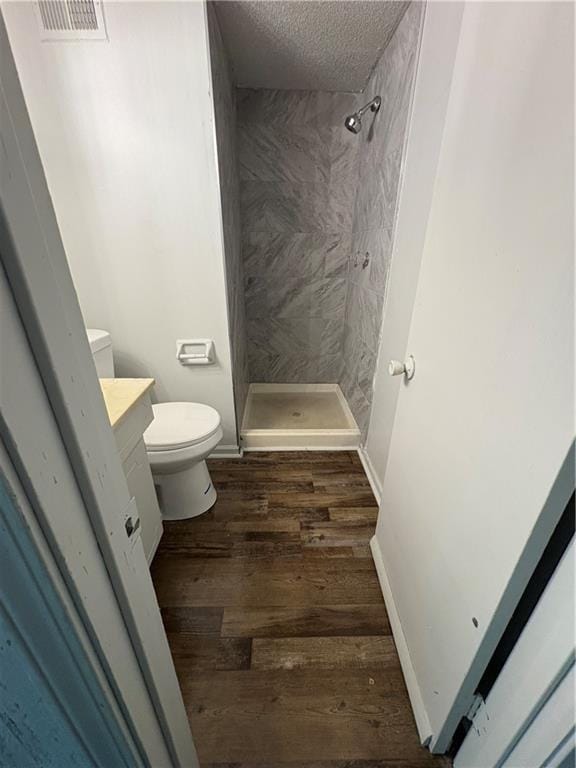 bathroom with vanity, toilet, a textured ceiling, visible vents, and a stall shower