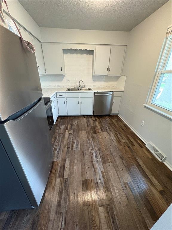 kitchen with visible vents, dark wood-style flooring, light countertops, a sink, and stainless steel appliances