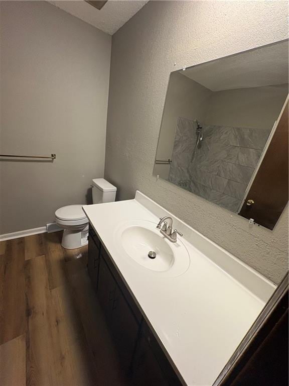 full bath with a shower, wood finished floors, vanity, toilet, and a textured wall