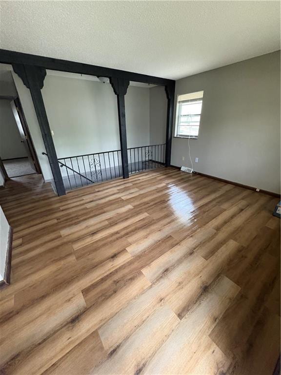 spare room with baseboards, a textured ceiling, visible vents, and wood finished floors