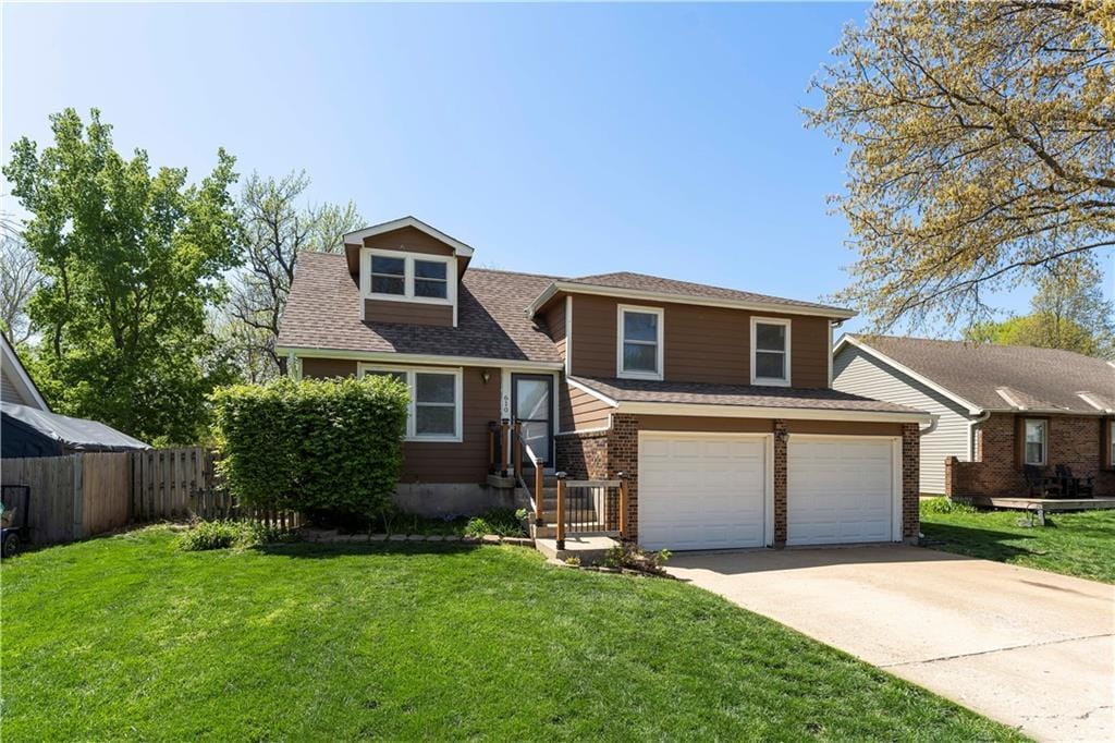 610 N Elm St, Gardner, KS 66030 - tri-level home featuring driveway, fence, a front yard, a garage, and brick siding