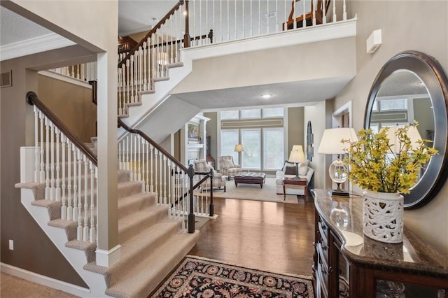 foyer featuring visible vents, baseboards, stairs, and a high ceiling
