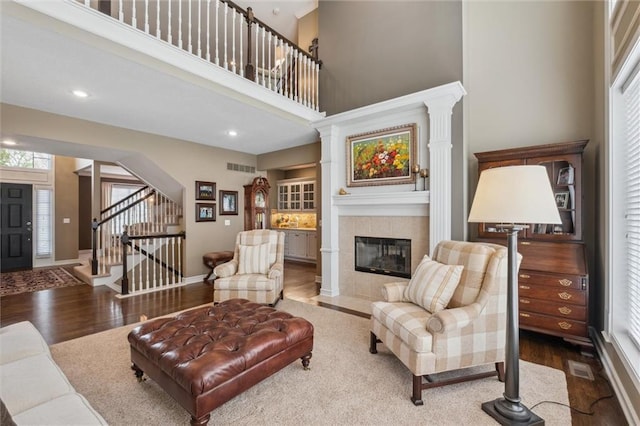 living area featuring visible vents, stairs, wood finished floors, plenty of natural light, and a tile fireplace