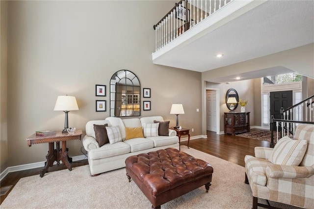 living room with baseboards, a high ceiling, stairs, and wood finished floors