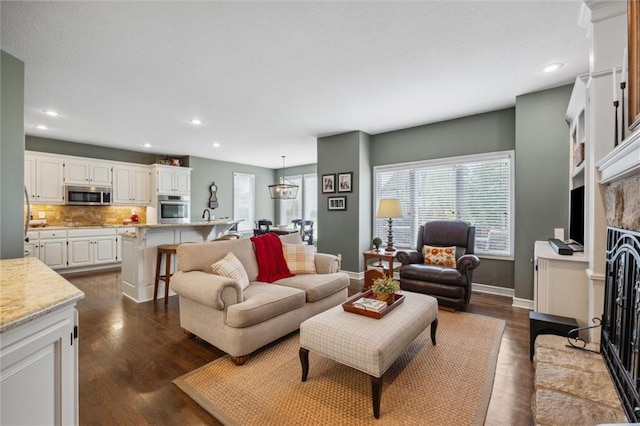 living area featuring recessed lighting, baseboards, dark wood finished floors, and a fireplace