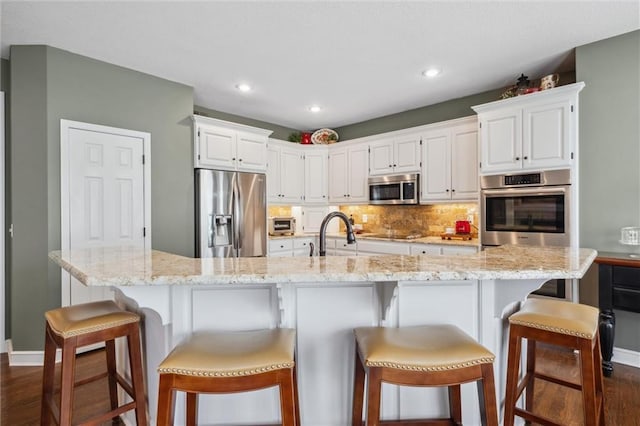 kitchen with light stone countertops, baseboards, dark wood-type flooring, white cabinets, and appliances with stainless steel finishes