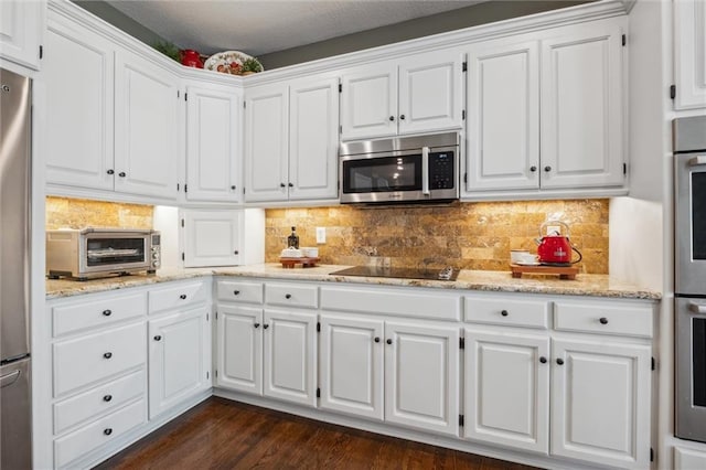 kitchen featuring a toaster, appliances with stainless steel finishes, white cabinets, and light stone counters