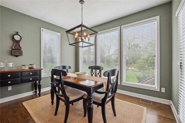 dining room featuring baseboards, dark wood-type flooring, a chandelier, and visible vents