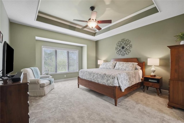 bedroom featuring crown molding, carpet floors, a ceiling fan, baseboards, and a tray ceiling