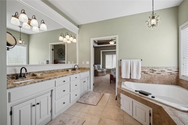ensuite bathroom featuring double vanity, a sink, a garden tub, and tile patterned floors