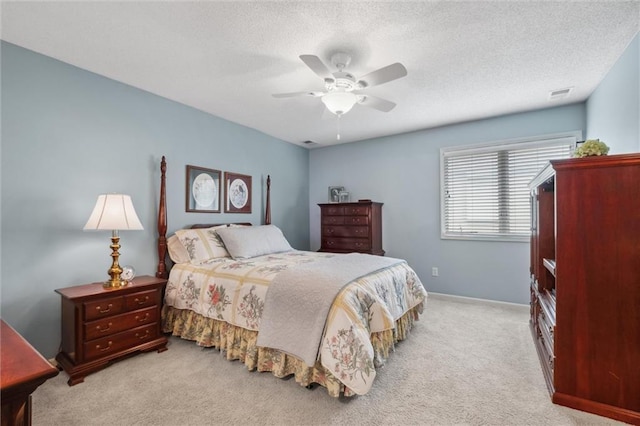 carpeted bedroom with visible vents, a textured ceiling, and ceiling fan