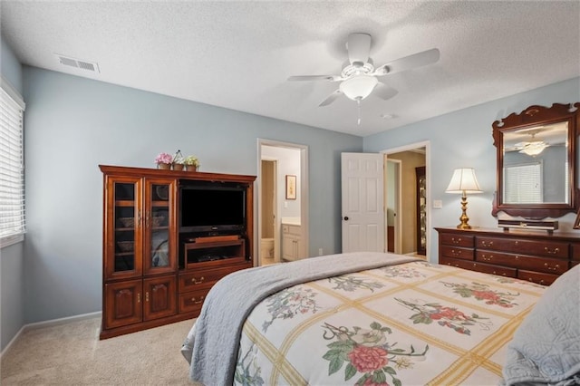 carpeted bedroom with ceiling fan, a textured ceiling, visible vents, baseboards, and ensuite bathroom