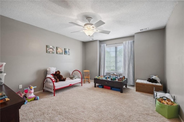 carpeted bedroom featuring ceiling fan, a textured ceiling, and visible vents