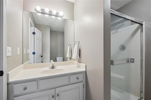 bathroom featuring toilet, a shower stall, and vanity