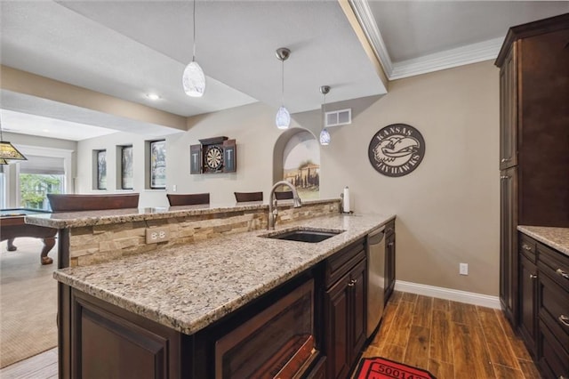 kitchen featuring a sink, a peninsula, baseboards, stainless steel dishwasher, and visible vents
