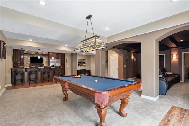 game room featuring arched walkways, baseboards, light carpet, and indoor bar