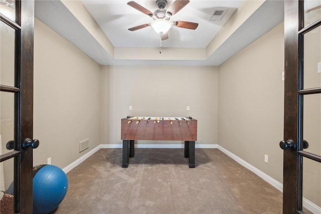 playroom featuring visible vents, a ceiling fan, baseboards, a raised ceiling, and carpet flooring