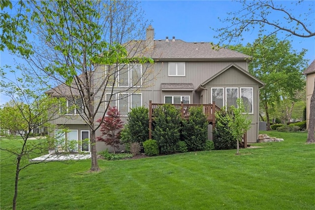 rear view of property with a wooden deck, a yard, and a chimney