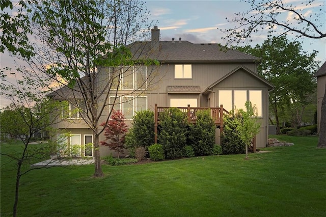 rear view of property with a lawn, a wooden deck, and a chimney