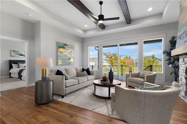 living room featuring light wood finished floors, beamed ceiling, a ceiling fan, and a healthy amount of sunlight