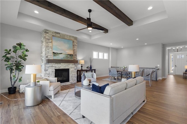 living area featuring a fireplace, baseboards, beamed ceiling, and wood finished floors