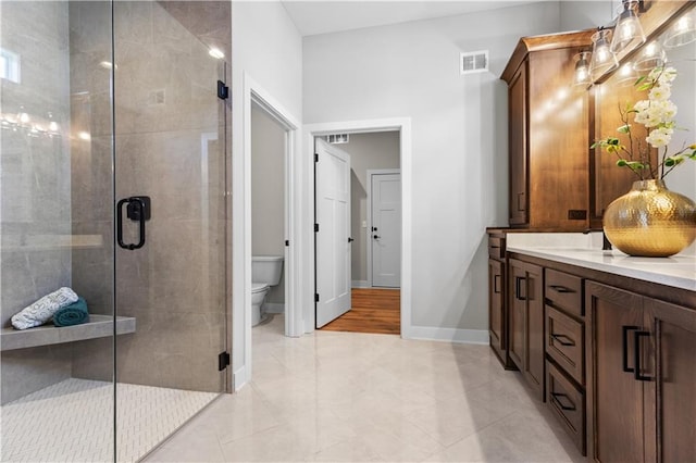 full bath featuring visible vents, toilet, a stall shower, double vanity, and baseboards