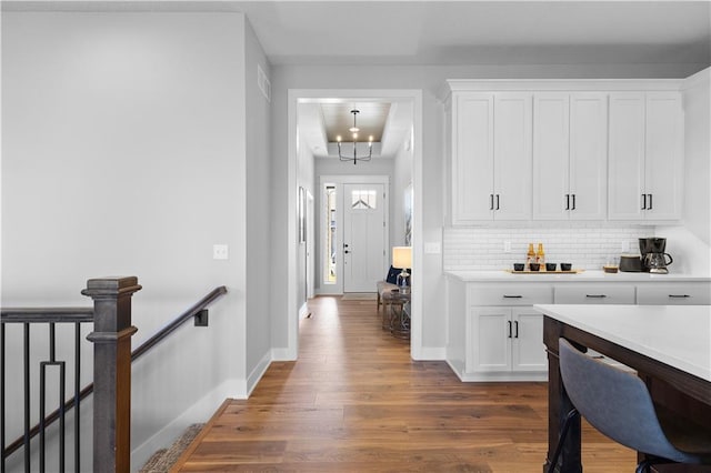 kitchen with white cabinets, dark wood-type flooring, light countertops, and backsplash