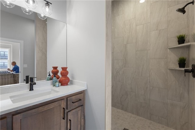 full bathroom featuring a tile shower and vanity